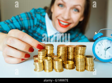 Salvataggio, donna sorridente di impilamento delle monete in oro in colonne Foto Stock