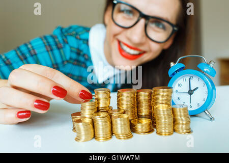 Salvataggio, donna sorridente di impilamento delle monete in oro in colonne Foto Stock