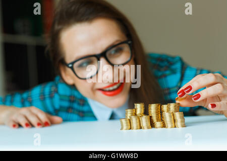 Salvataggio, donna sorridente di impilamento delle monete in oro in colonne Foto Stock