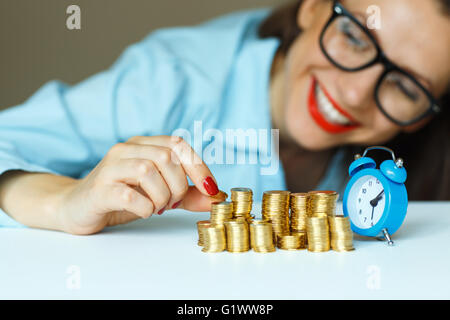 Salvataggio, donna sorridente di impilamento delle monete in oro in colonne Foto Stock