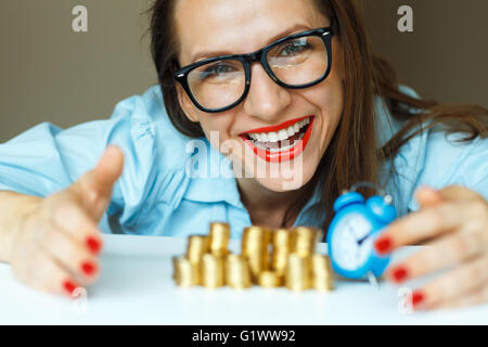 Salvataggio, donna sorridente di impilamento delle monete in oro in colonne Foto Stock
