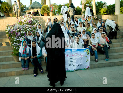 Un gruppo di studentesse con il loro chador-placcati docente su una serata visita alla tomba del poeta locale Hafez di Shiraz, Iran Foto Stock