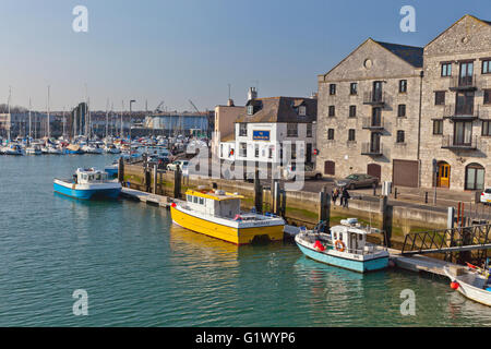 Due pescherecci colorati sono ormeggiati a fianco di un vecchio magazzino nel porto di Weymouth Dorset, England, Regno Unito Foto Stock