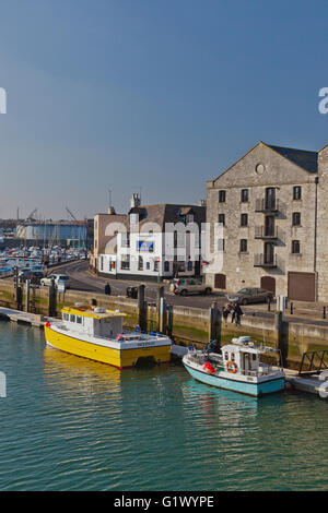 Due pescherecci colorati sono ormeggiati a fianco di un vecchio magazzino nel porto di Weymouth Dorset, England, Regno Unito Foto Stock