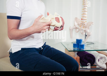 Un fisioterapista è in possesso di un modello di un bacino umano Foto Stock