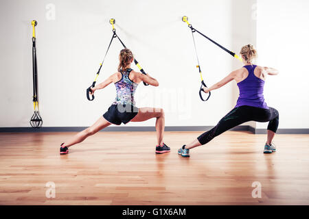 Due giovani donne stanno facendo esercizi di peso corporeo con cinghie di fissaggio Foto Stock