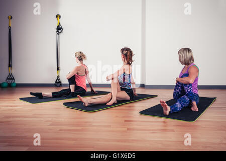 Un piccolo gruppo di donne stanno allungando le spalle in palestra Foto Stock