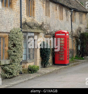 Tradizionale cabina telefonica rossa inglese all'esterno dei cottage calcarei nella piazza del villaggio di Montacute, Somerset, Inghilterra, Regno Unito Foto Stock