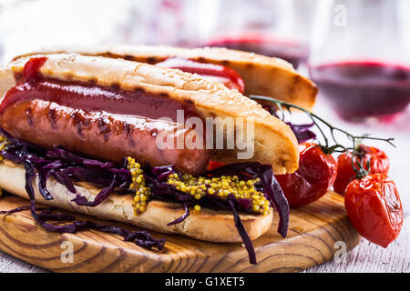 Salsicce alla griglia in sandwich con cavoli rossi dolci coleslaw, la senape e la salsa di pomodoro sulla tavola di legno Foto Stock