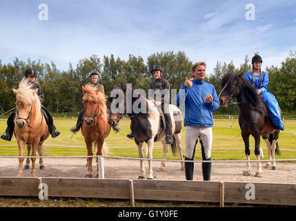 Selfoss, Sud dell'Islanda, dell'Islanda. Il 4° agosto 2015. Al Fridheimar family run farm a Selfoss, Sud dell'Islanda, con quattro dei suoi cinque bambini su cavalli dietro di lui, proprietario di fattoria Rafn KnÃºtur Ãrmann parla ai visitatori prima di un equino di prestazioni. Oltre l'orticoltura, la fattoria di famiglia offre ai visitatori uno spettacolo di cavalli con l'islandese razza di cavalli portati dai primi coloni dalla Scandinavia intorno al 900 D.C. Il turismo è un settore in crescita dell'economia con l'Islanda di diventare una destinazione turistica preferita. © Arnold Drapkin/ZUMA filo/Alamy Live News Foto Stock