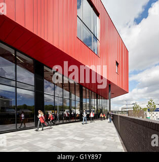 Vista lungo piano terra vetri e rosso rivestimento in acciaio. Plymouth Creative School of Art di Plymouth, Regno Unito. Architetto: Feilden Clegg Bradley Studios LLP, 2015. Foto Stock