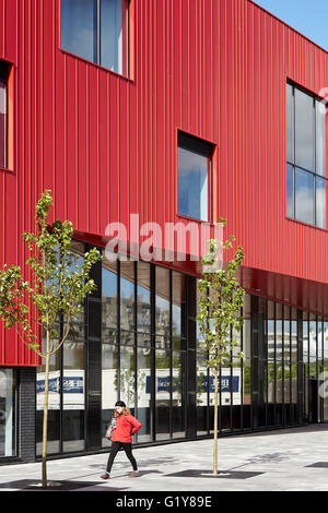 Vista lungo piano terra vetri e rosso rivestimento in acciaio. Plymouth Creative School of Art di Plymouth, Regno Unito. Architetto: Feilden Clegg Bradley Studios LLP, 2015. Foto Stock
