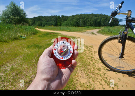 Con una bussola e una bicicletta forcella anteriore. Orientamento durante un giro in bicicletta in zone rurali. Foto Stock