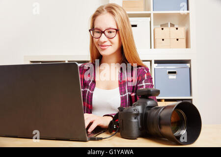 Fotografo con fotocamera reflex digitale e il computer portatile nel suo ufficio Foto Stock