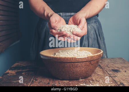 Una giovane donna è in piedi con una manciata di avena Foto Stock