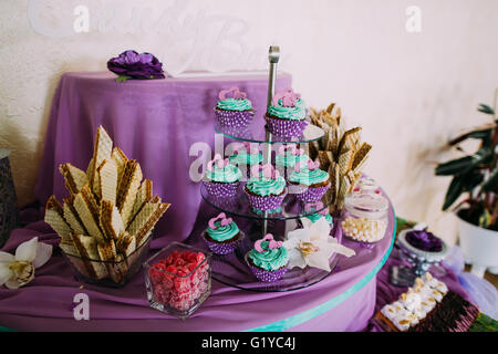 Set di diversi e deliziosi dolci di lavanda tortine sulla torta divertente-stand, backgraund viola Foto Stock