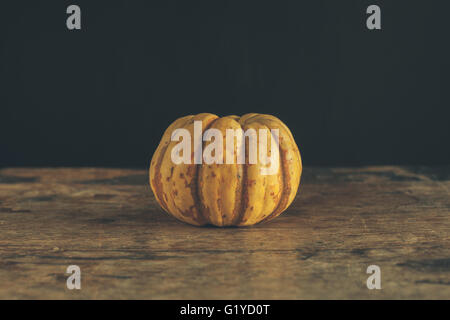 Una zucca su di un tavolo di legno Foto Stock