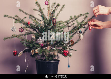 Le mani la decorazione di un albero di natale con tutti i tipi di cose colorate Foto Stock