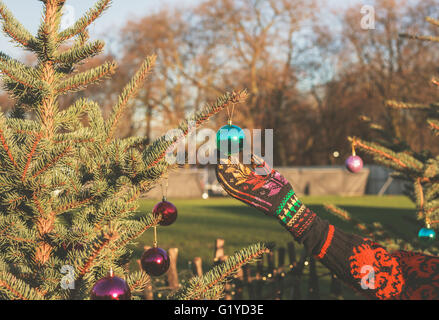 Una mano è di toccare la pallina appeso a un albero di Natale al di fuori Foto Stock