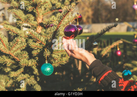 Una mano è di toccare la pallina appeso a un albero di Natale al di fuori Foto Stock