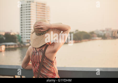 Una giovane donna è ammirando il tramonto sul fiume a Bangkok, in Thailandia Foto Stock