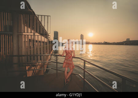 Una giovane donna è ammirando il tramonto sul fiume a Bangkok, in Thailandia Foto Stock