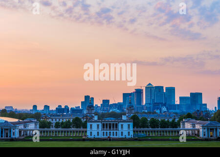 Vista di Queens House e Canary Wharf da Greenwich Park, Londra con un cielo al tramonto Foto Stock
