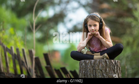 Bambina con le cuffie premurosamente salotto all'aperto. Foto Stock