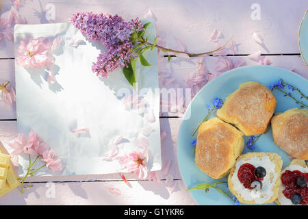 Bella colazione a molla con uno sfondo con scones scozzese, lilla e fiori di ciliegio Foto Stock