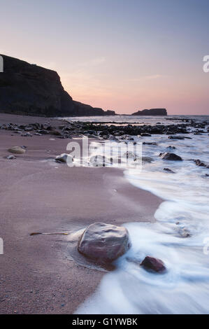 Mare calmo, onde, sabbia costa rocciosa, stagliano cliffs & Saltwick Nab sotto il cielo rosso al tramonto - scenic Saltwick tranquilla baia, Yorkshire, Regno Unito. Foto Stock