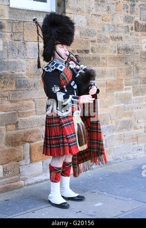 Uno scozzese che indossa il vestito tradizionale riproduzione di cornamuse al di fuori al di fuori del Castello di Edimburgo lungo la Royal Mile Foto Stock