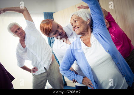 Gruppo di anziani a fare gli esercizi con un infermiere Foto Stock