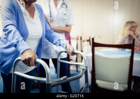 Un infermiere che assiste un senior usando un walker Foto Stock