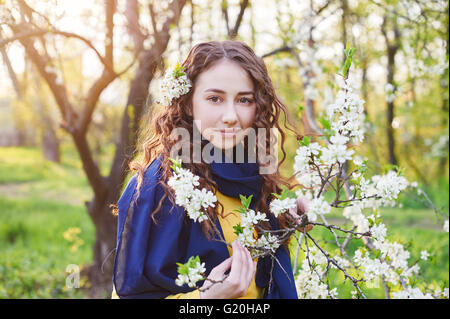 Giovane e bella donna che cammina in un fiorente giardino di primavera Foto Stock