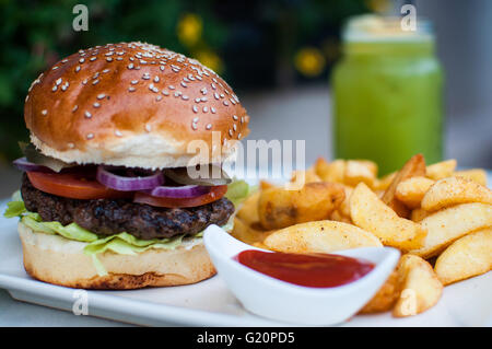 Burger con patate e salsa di pomodori - un close-up per millenials Foto Stock