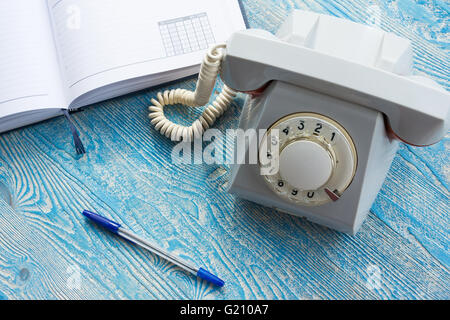 La foto illustra un telefono di rete fissa con un notebook Foto Stock