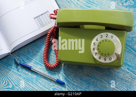 La foto illustra un telefono di rete fissa con un notebook Foto Stock