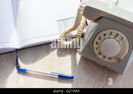 La foto illustra un telefono di rete fissa con un notebook Foto Stock