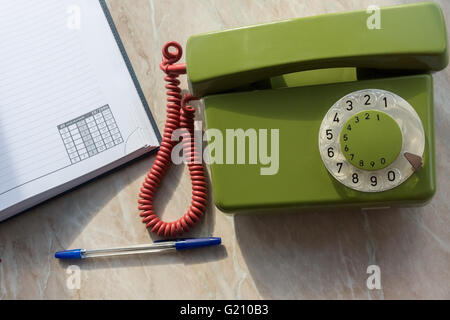 La foto illustra un telefono di rete fissa con un notebook Foto Stock