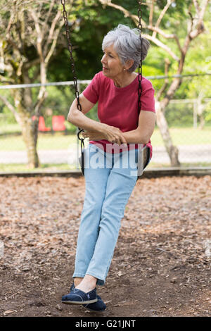 Senior lady su altalena in pensiero profondo contemplando il relax Foto Stock