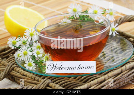 Benvenuti a casa carta con la tazza di tè camomilla con freschi Fiori di camomilla e limone Foto Stock