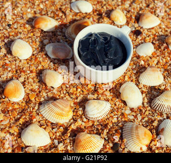 Fango del Mar Morto per trattamenti spa in una tazza sulla spiaggia con shell Foto Stock