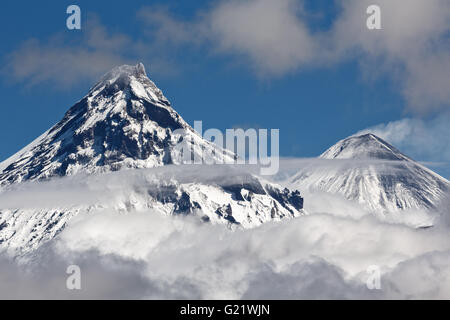 Bellissimo paesaggio vulcanico: vista sul vulcano Kamen e attivo vulcano Klyuchevskoy sopra le nuvole. Russia, Kamchatka regione. Foto Stock