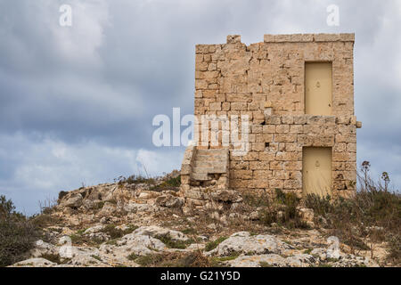 Sulla sommità della collina a Dingli Cliffs, isola di Malta, una vecchia casa fatta di pietre. Cielo Molto nuvoloso in background. Foto Stock