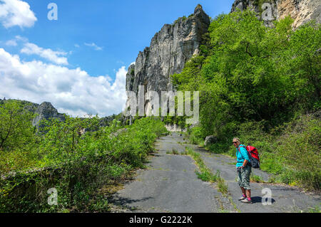 Femmina con walker red zaino camminando sulla vecchia strada Pas de L'Escalette, Herault, Languedoc Roussillon, Francia Foto Stock