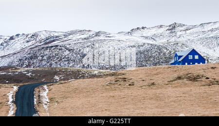 Tipico paesaggio islandese alla penisola di Reykjanes con montagne coperte di neve strada che conduce ad un blu casa cottage Foto Stock