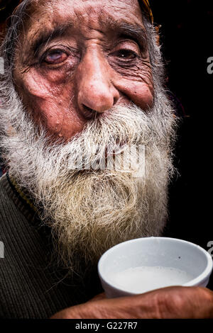 Il vecchio uomo di bere il latte sulla strada di Delhi, India Foto Stock