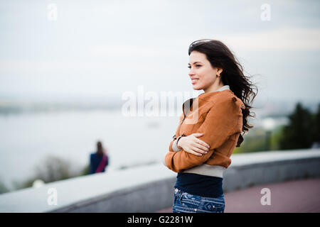 Bello pensieroso giovane azienda smart phone e guardarlo mentre è seduto al cafe' all'aperto. Messa a fuoco selettiva. Foto Stock