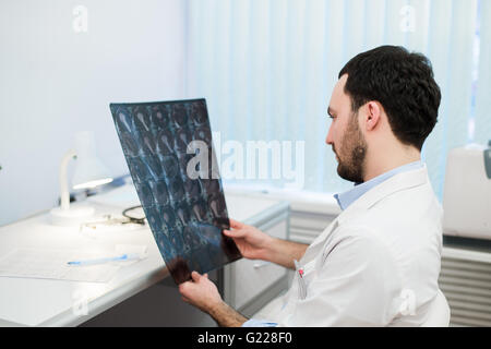 Giovane maschio medico di leggere e rivedere un cervello MRI scan Foto Stock