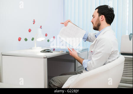 Medico che lavorano con i risultati di prova del suo paziente in ufficio Foto Stock